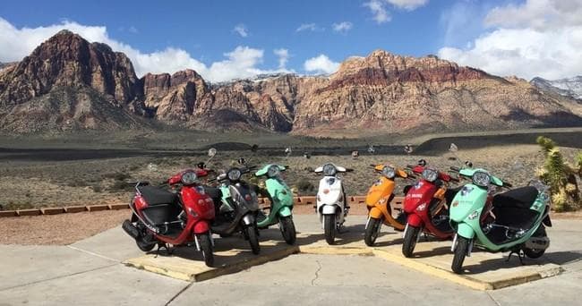 Rental scooters lined up against desert mountain backdrop