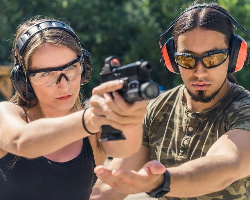 Instructor guiding shooter at outdoor pistol range during training