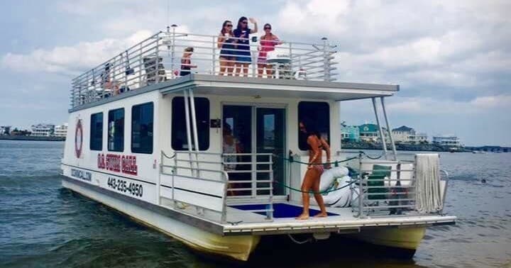 Charter party boat docked on coastal bay with passengers on roof