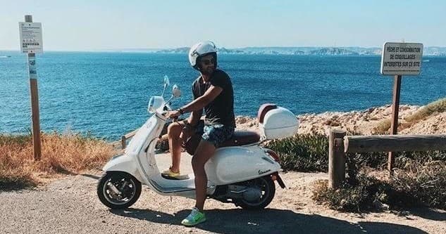 Rider on white Vespa along Mediterranean cliffside road