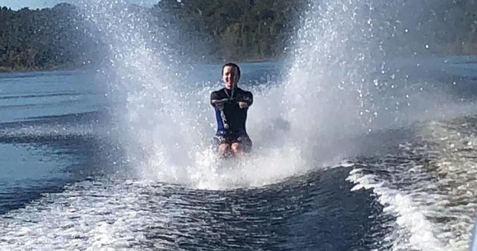 Waterskier creating dramatic spray on forested lake, action shot