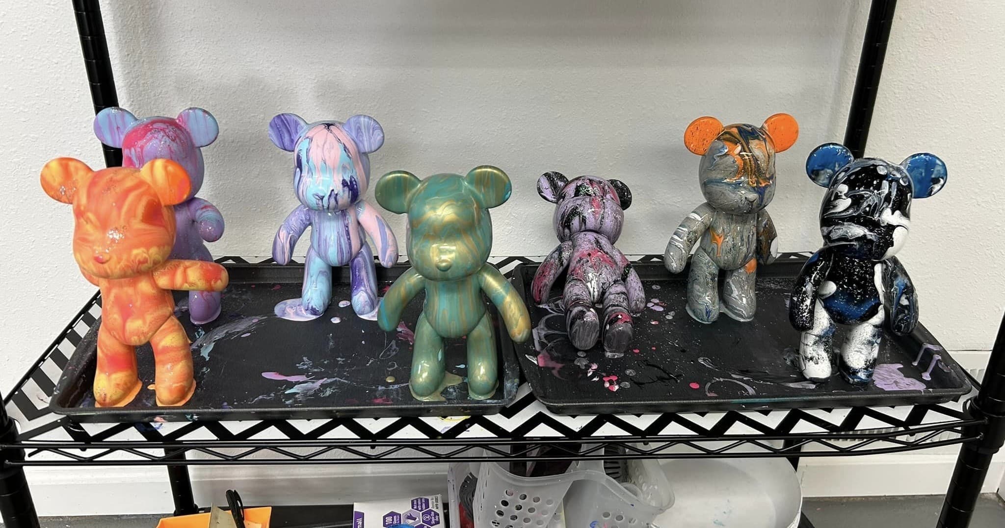 Row of painted vinyl bear figurines on studio shelf display