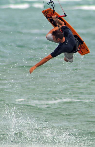Boarder performing aerial trick over blue ocean near Cabarete
