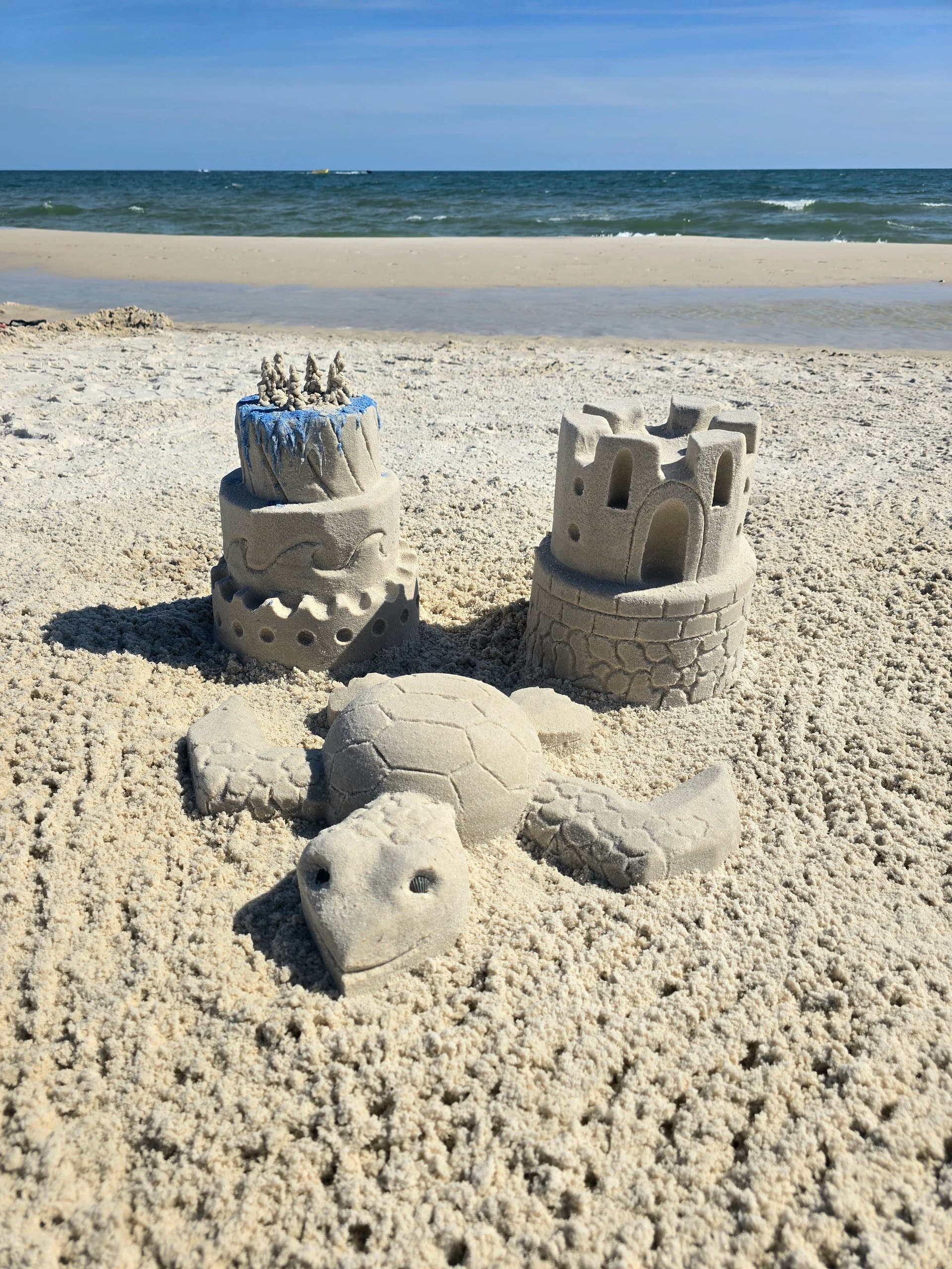 Sand turtle and small sandcastles on sunny ocean beach