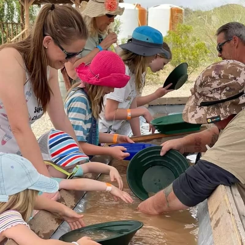 Families gold-panning at outdoor sluice at Vulture City