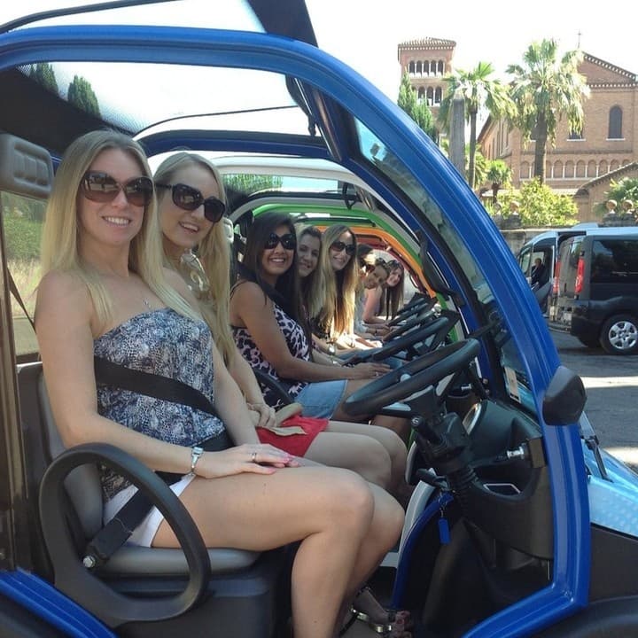 Women in electric mini-cars on a sunny Rome tour, smiling