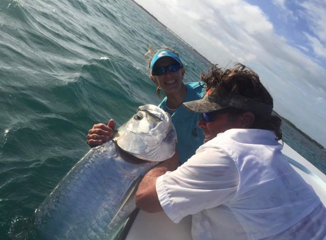 Fishermen landing large tarpon at boat on open ocean
