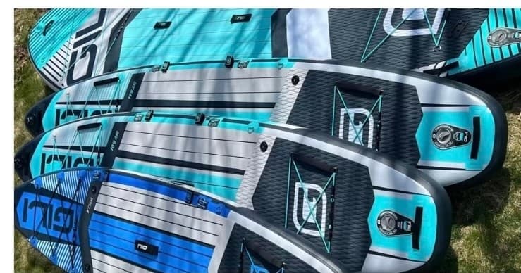 Close-up of stacked paddleboards with traction pads on grass