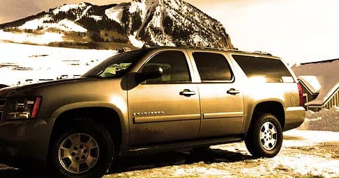 Gold SUV parked near snowy mountain pass for scenic drive