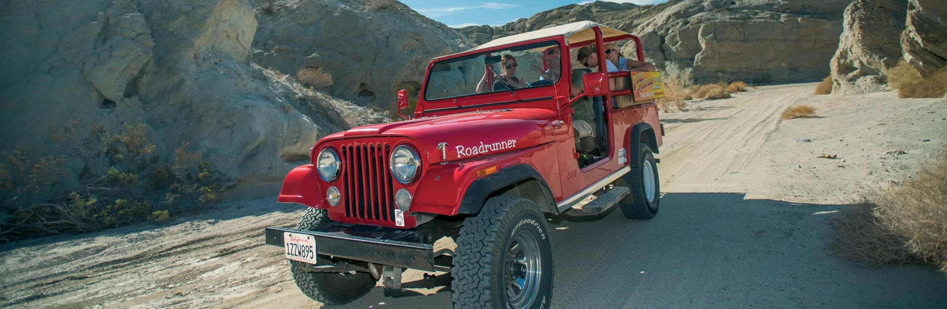 Red jeep driving across sandy desert canyon road expedition