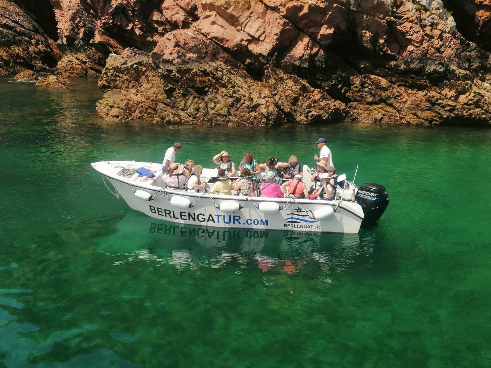 Small tour boat with passengers in emerald coastal waters