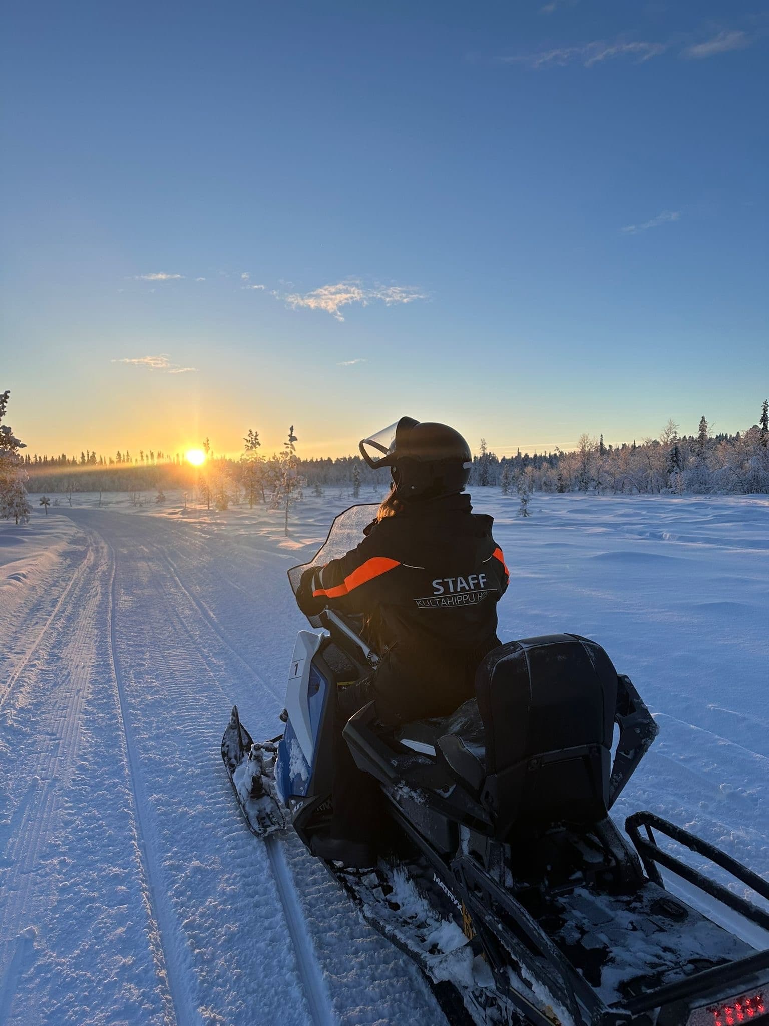 Rider on snowmobile cruising sunset trail, Arctic snow expedition