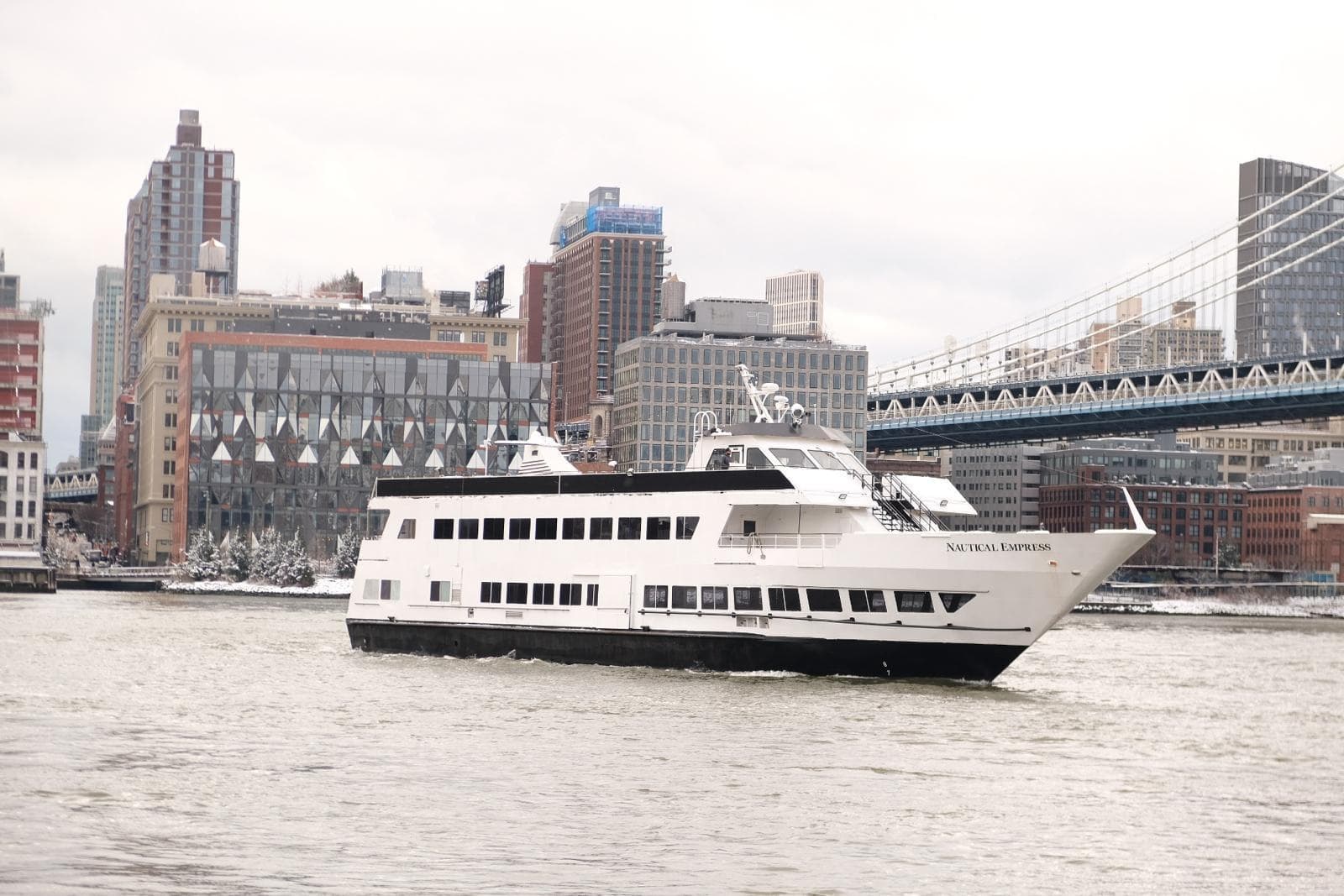 Sightseeing cruise boat on urban river with skyline and bridge
