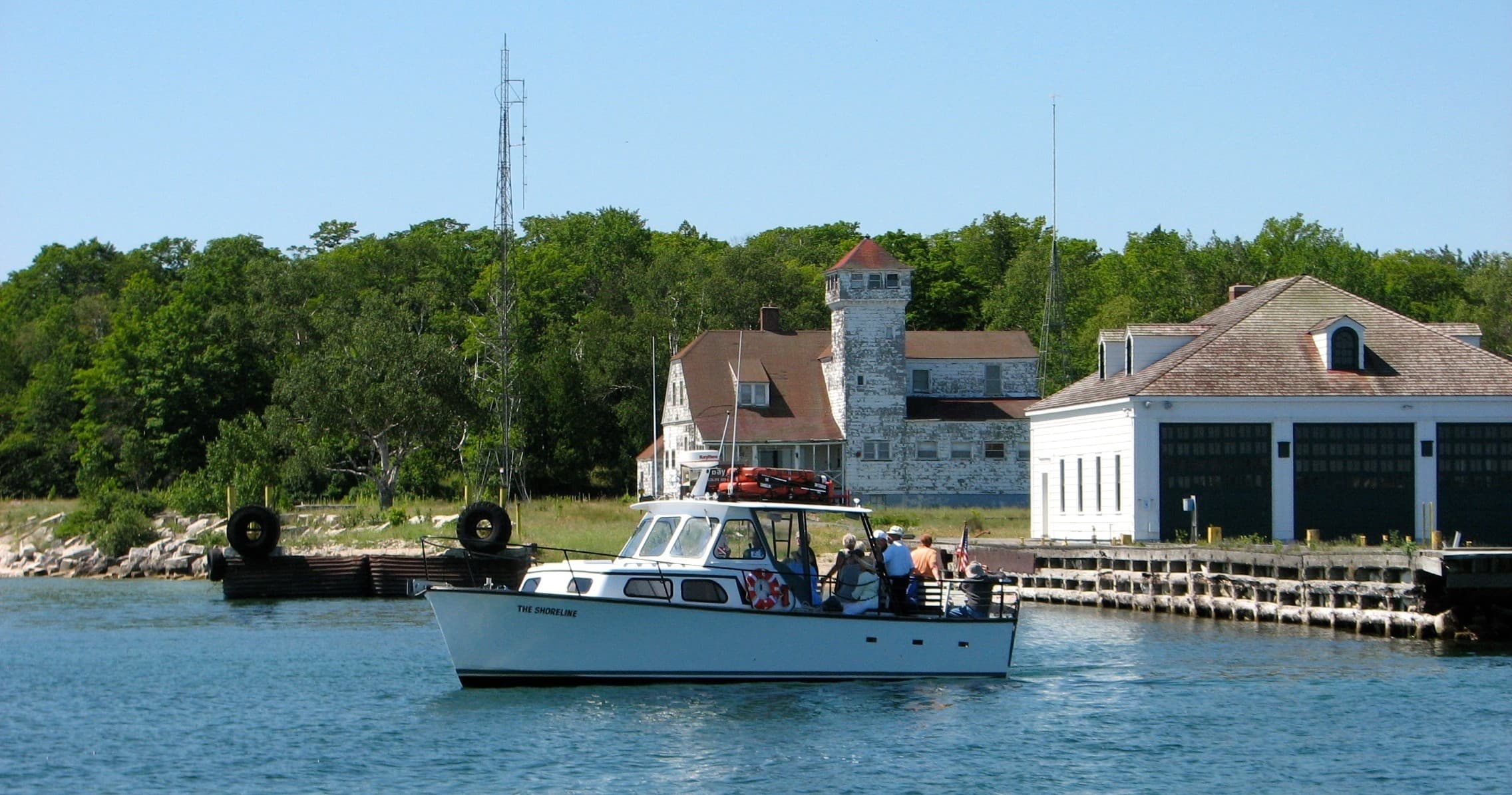 Small tour boat approaching harbor with historic shoreline buildings