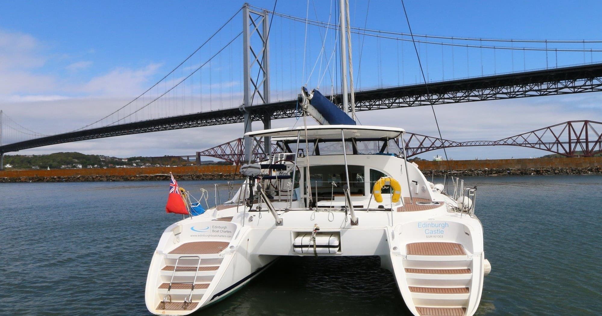 Twin-hulled catamaran framed by Forth Bridge, scenic sailing