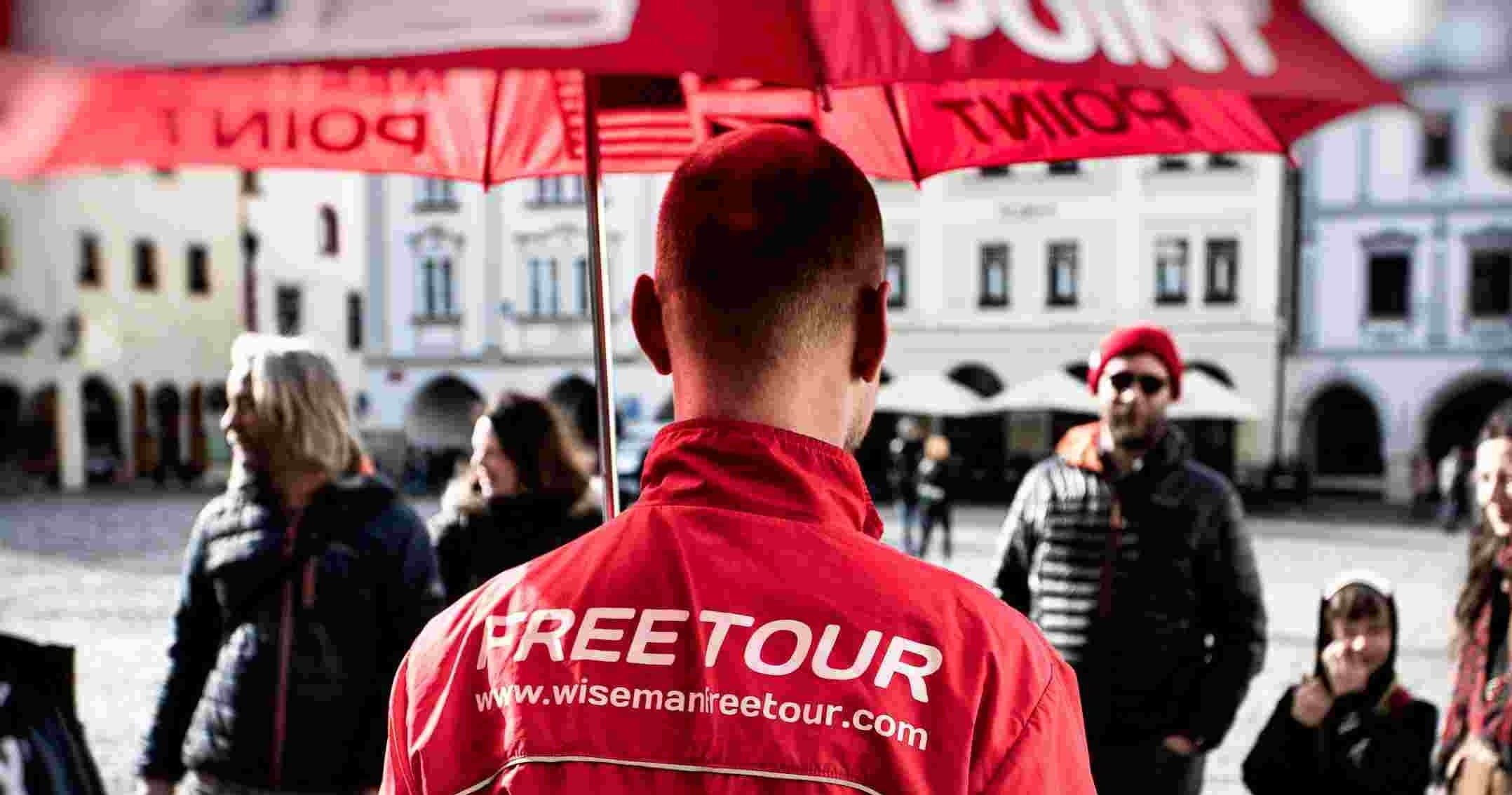 Free tour guide wearing red jacket in historic town square