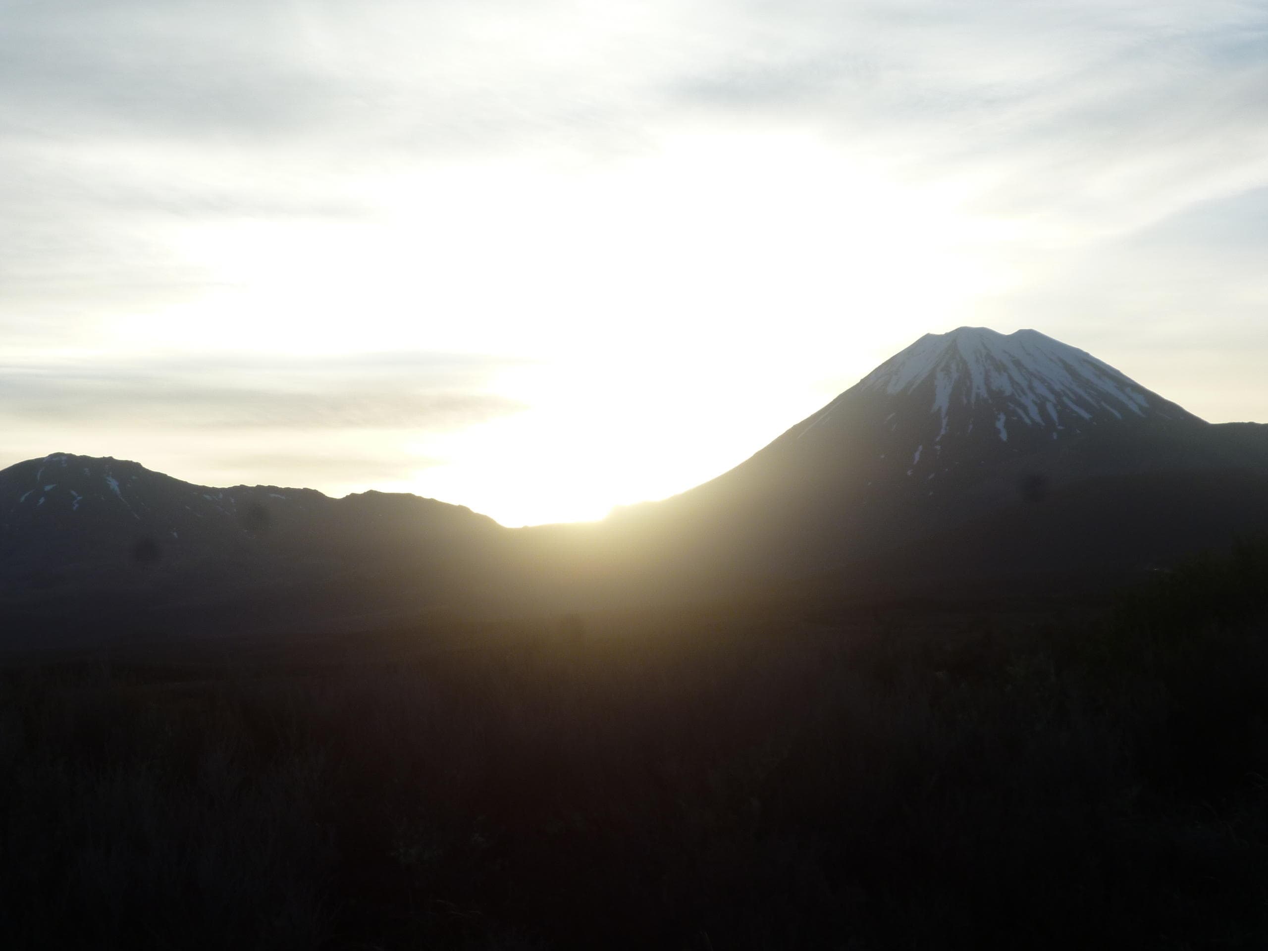 Sunrise over volcanic peak with silhouetted mountain ridge vista