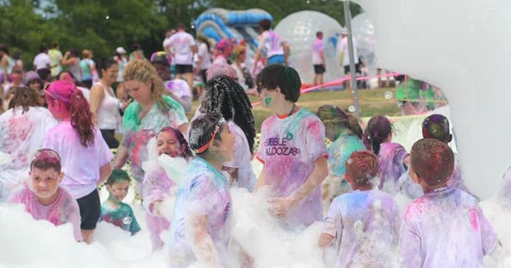 Kids playing in colorful foam at outdoor family fun run event