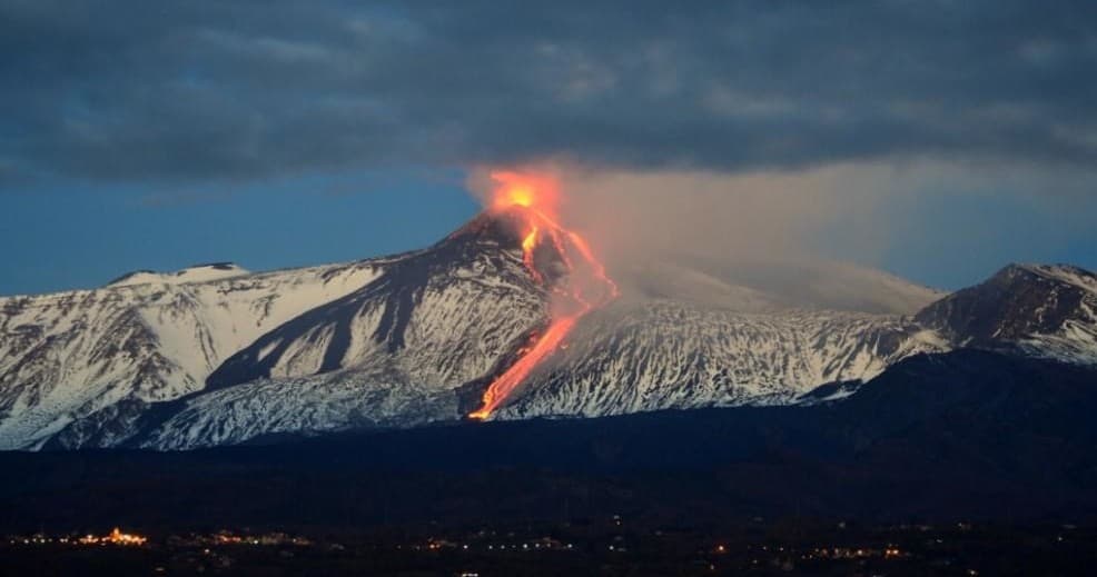 Erupting Mount Etna lava flow across night sky on Sicily coast