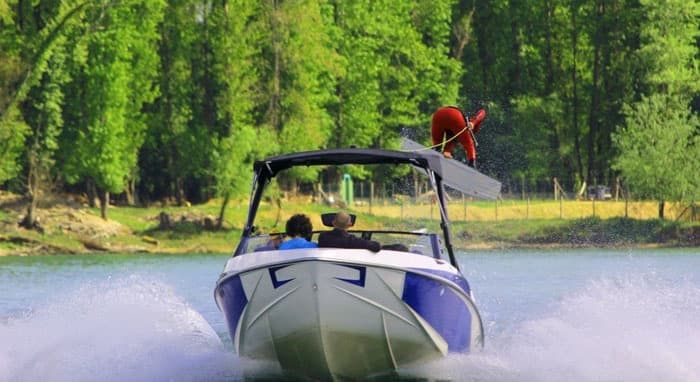 Bow-on motorboat approaching through green lakeside forest