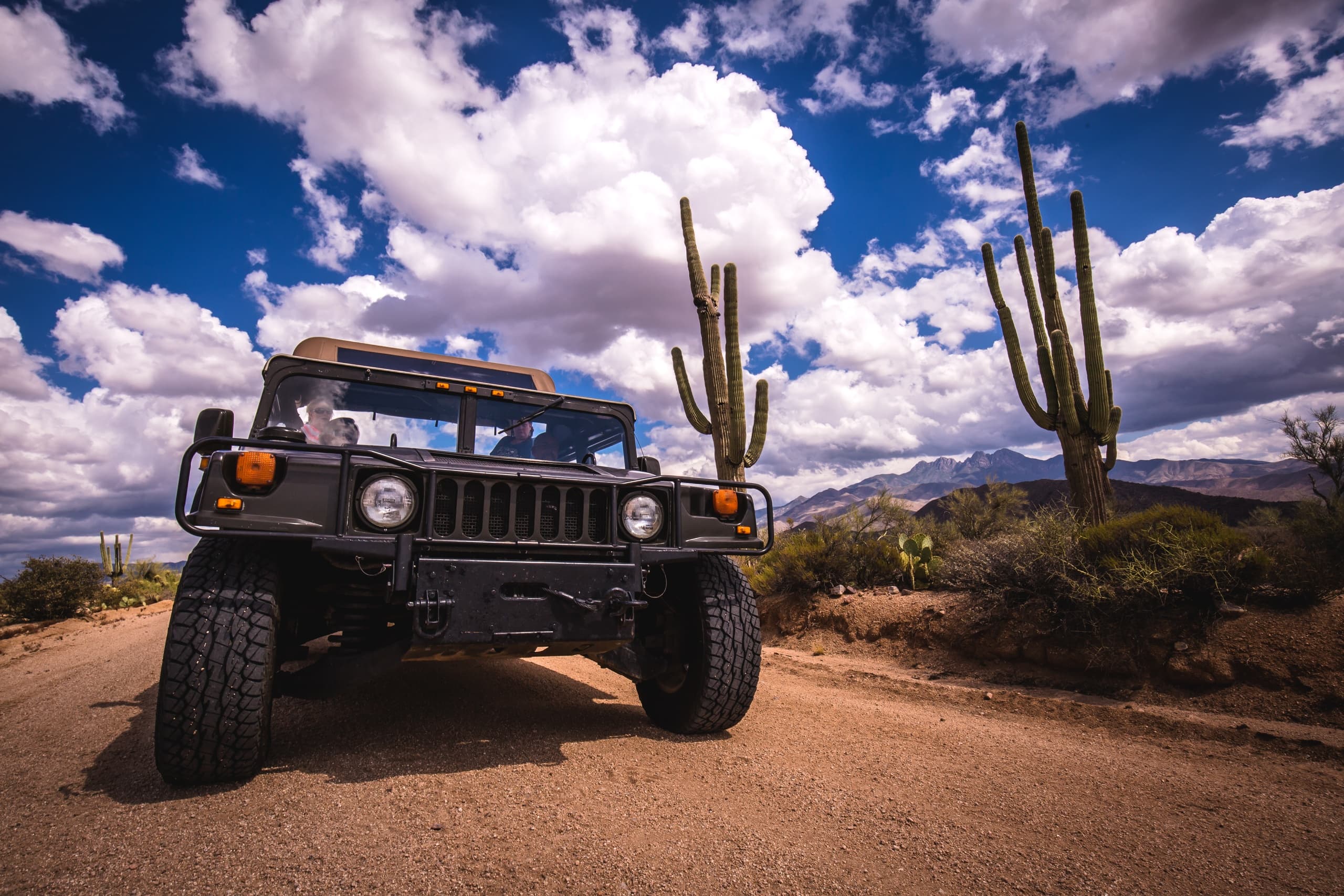 4x4 Jeep on wide desert road under dramatic cloudy sky vista