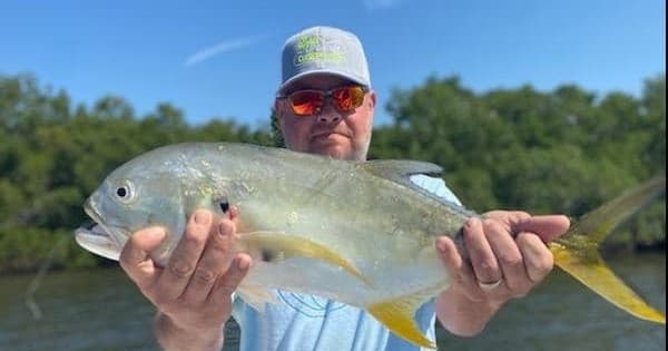 Angler holding large jack crevalle on shallow coastal flats