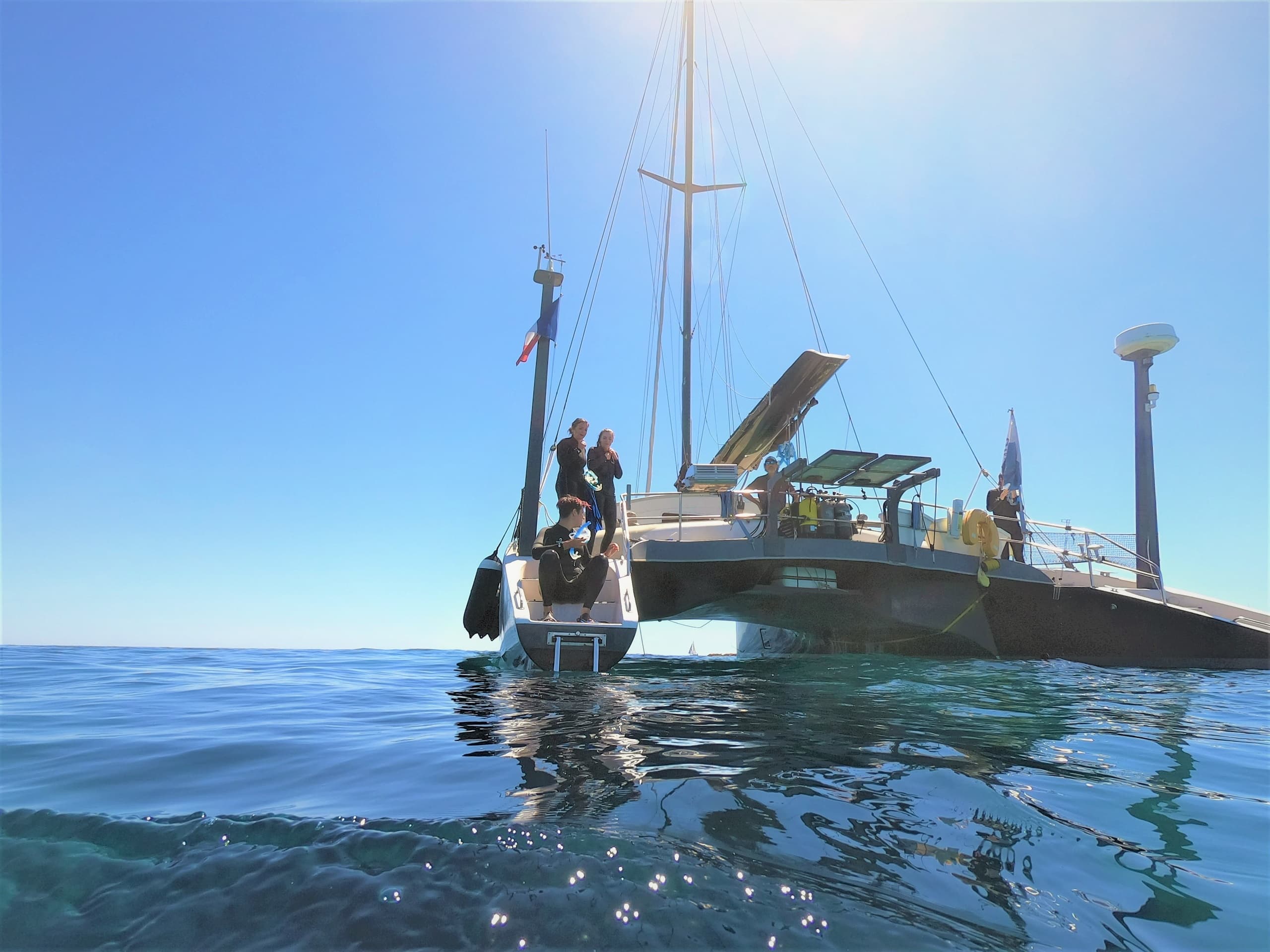 Catamaran anchored on open sea with passengers boarding