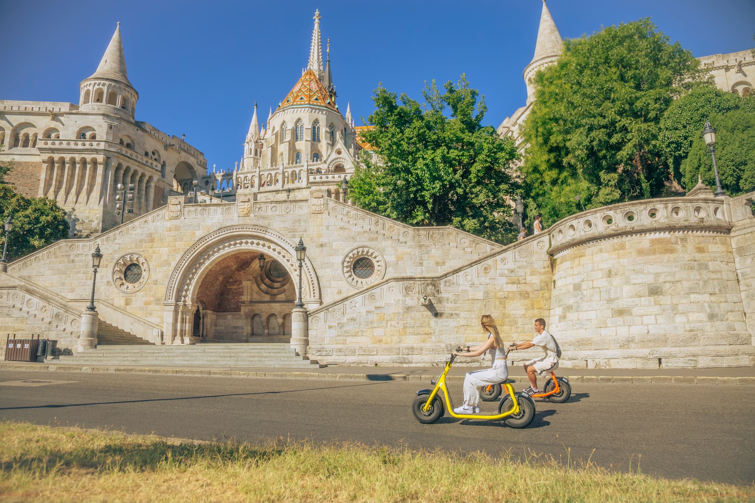 Couple riding e-scooter near Fisherman's Bastion historic terrace