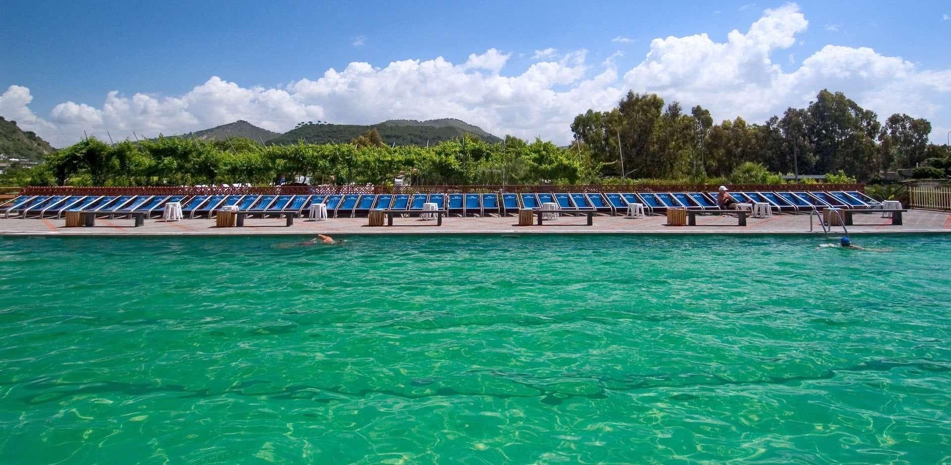 Beachfront sunbeds and pier on vibrant turquoise sea