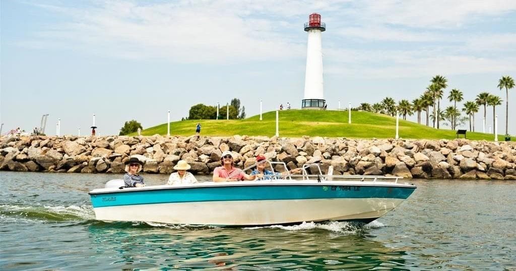 Motorboat cruising near Long Beach lighthouse, sunny harbor