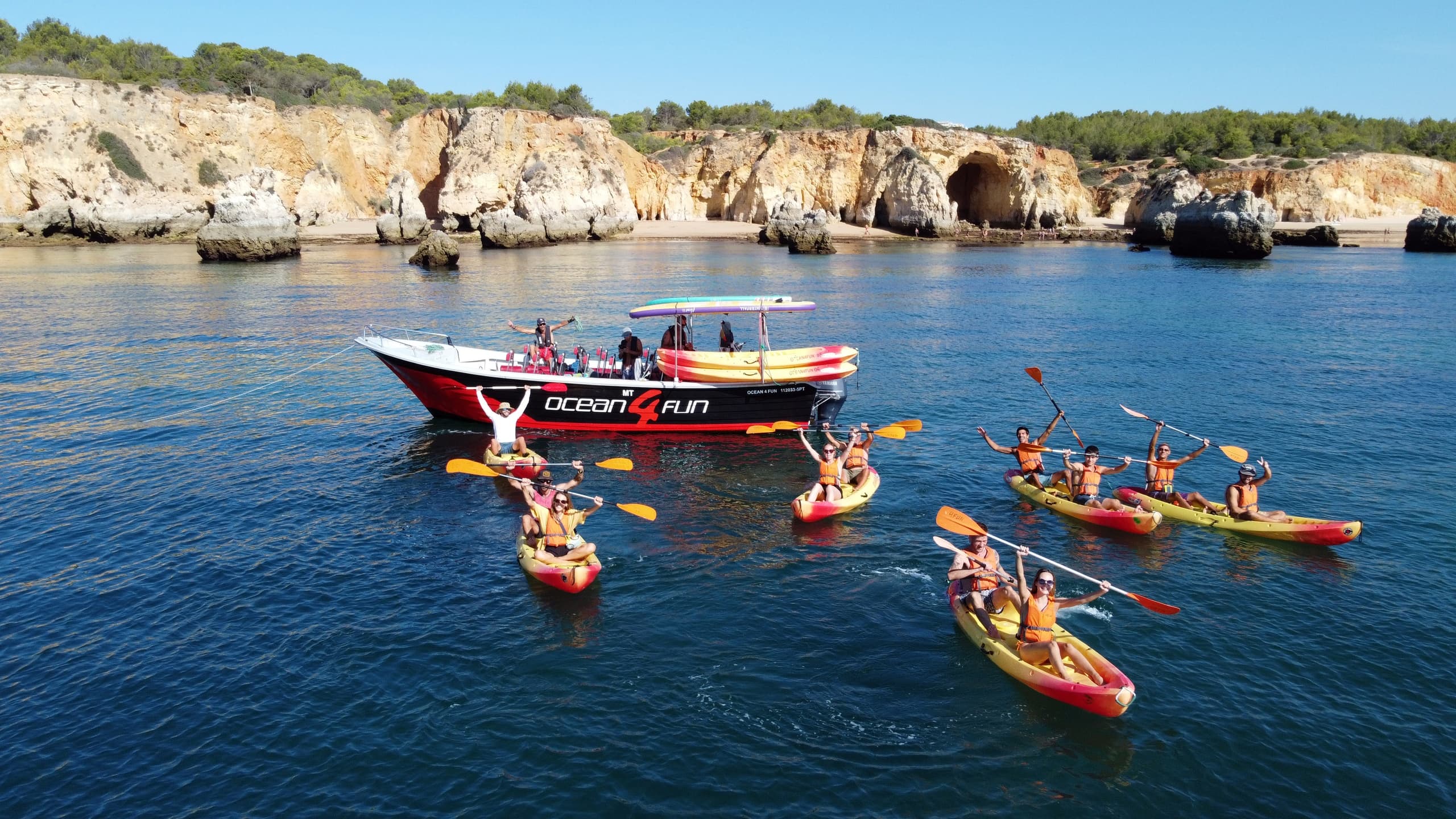 Guided kayak group near rocky Algarve cliffs on calm sea