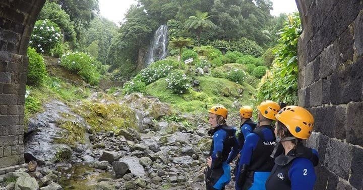 Guided canyon hike group observing waterfall in lush valley