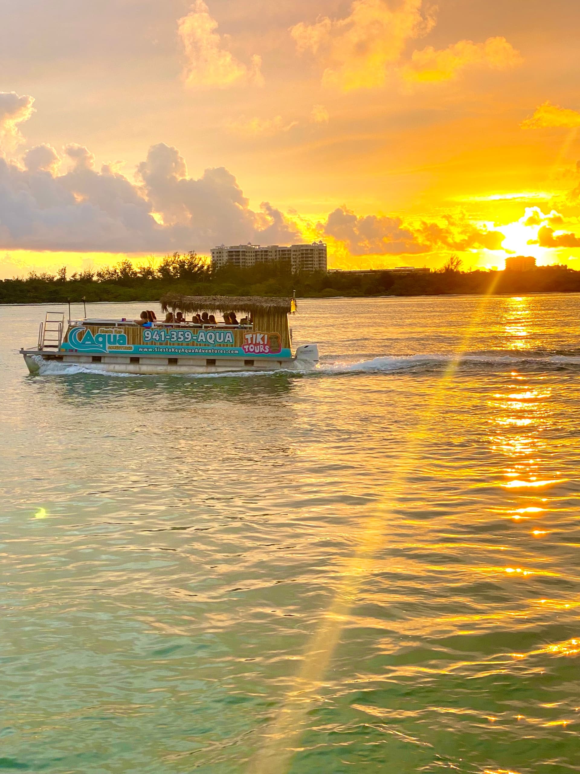 Sunset sightseeing boat cruising calm bay with golden reflections