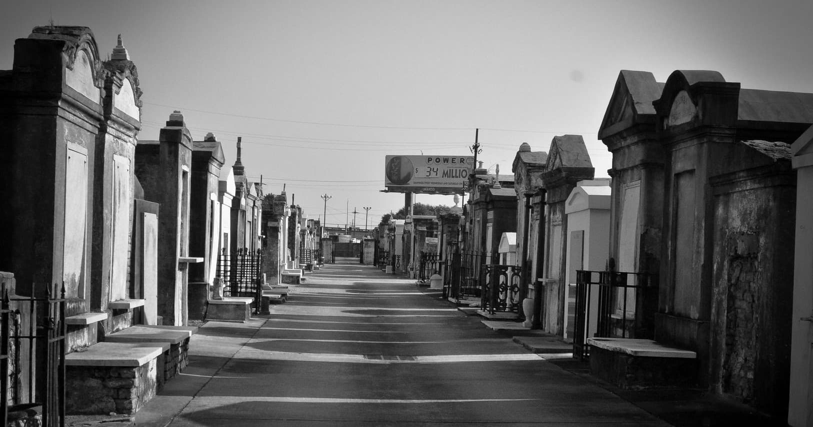 Historic above-ground mausoleums lining cemetery avenue, daytime