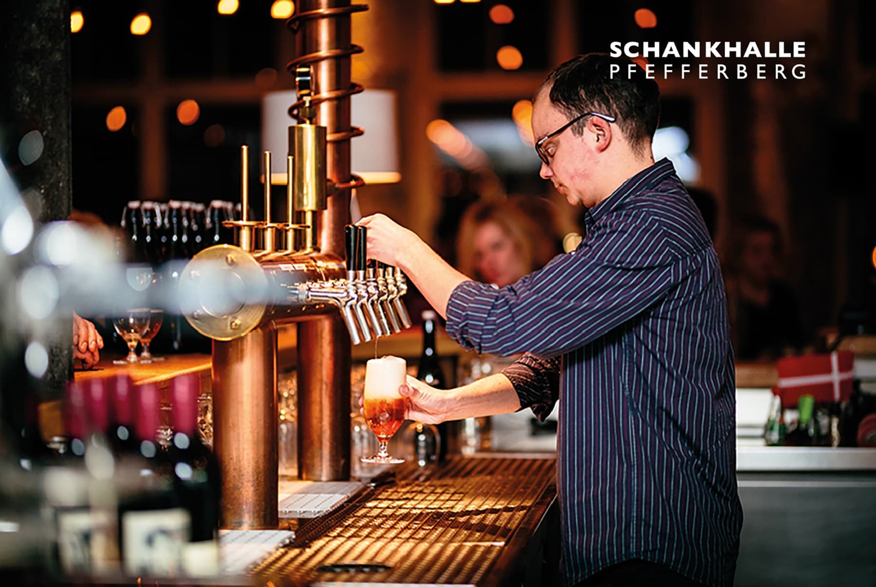 Bartender pouring draft beer at busy Schankhalle Pfefferberg bar
