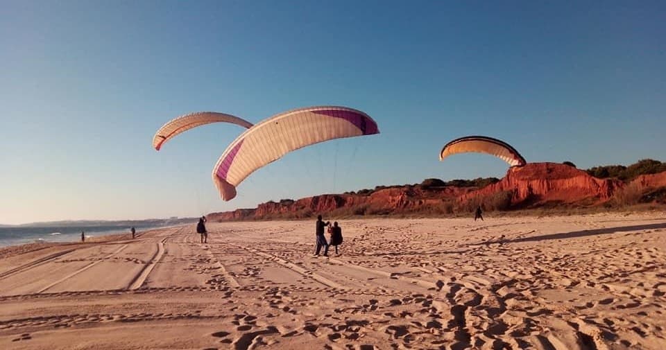Beach paragliding over sandy Algarve bay with scenic cliffs