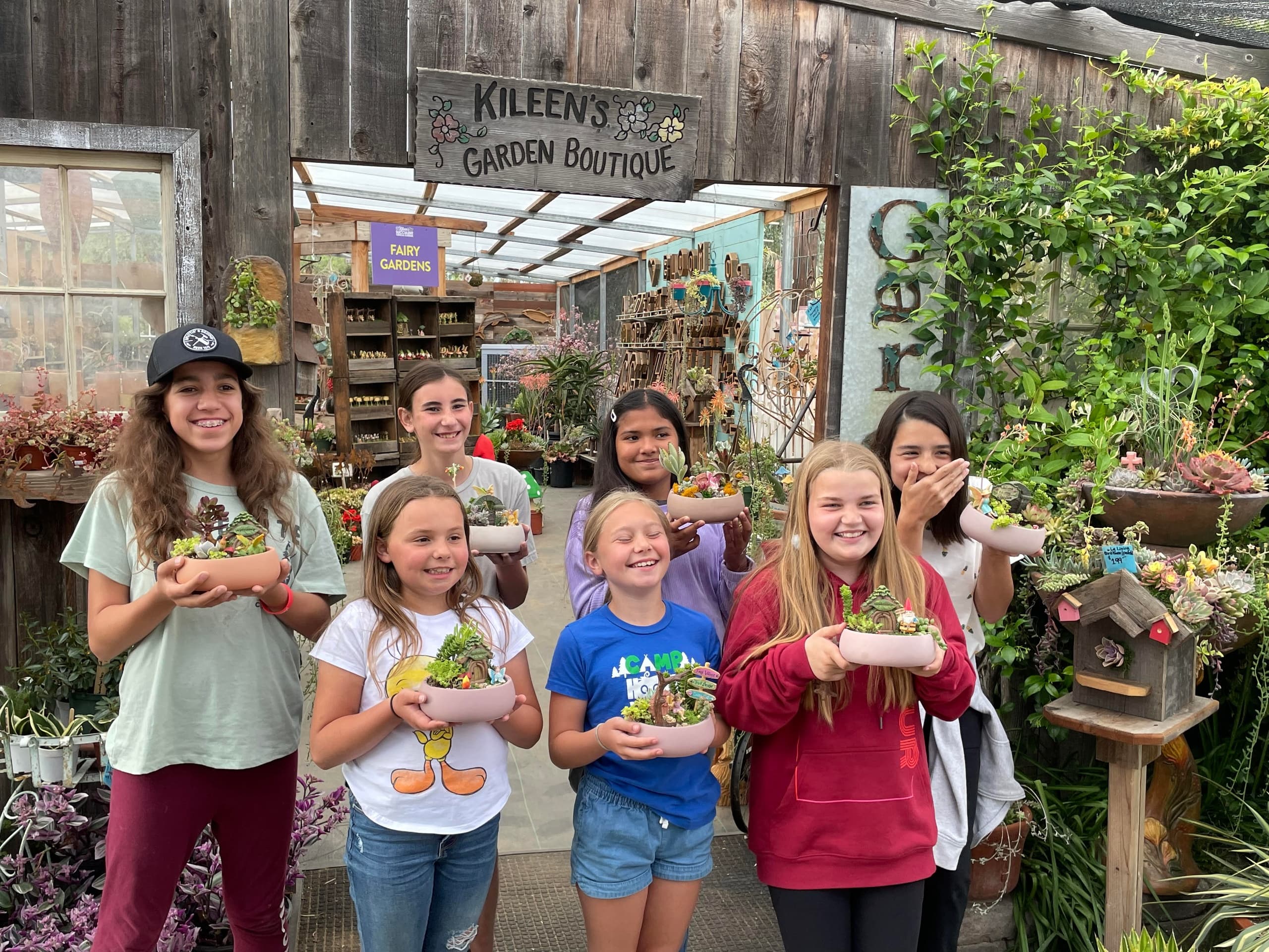 Kids holding succulent planters at garden boutique entrance
