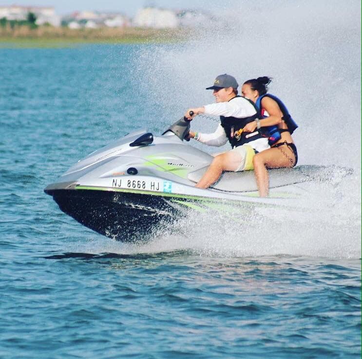 Two riders on jet ski speeding across blue harbor waters