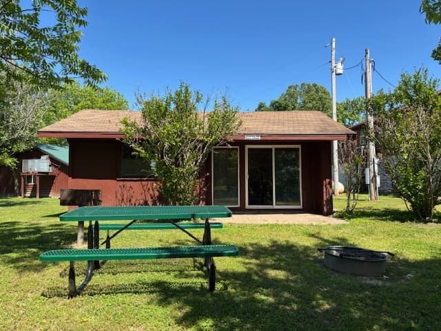 Cabin exterior with picnic table on grassy campsite lawn