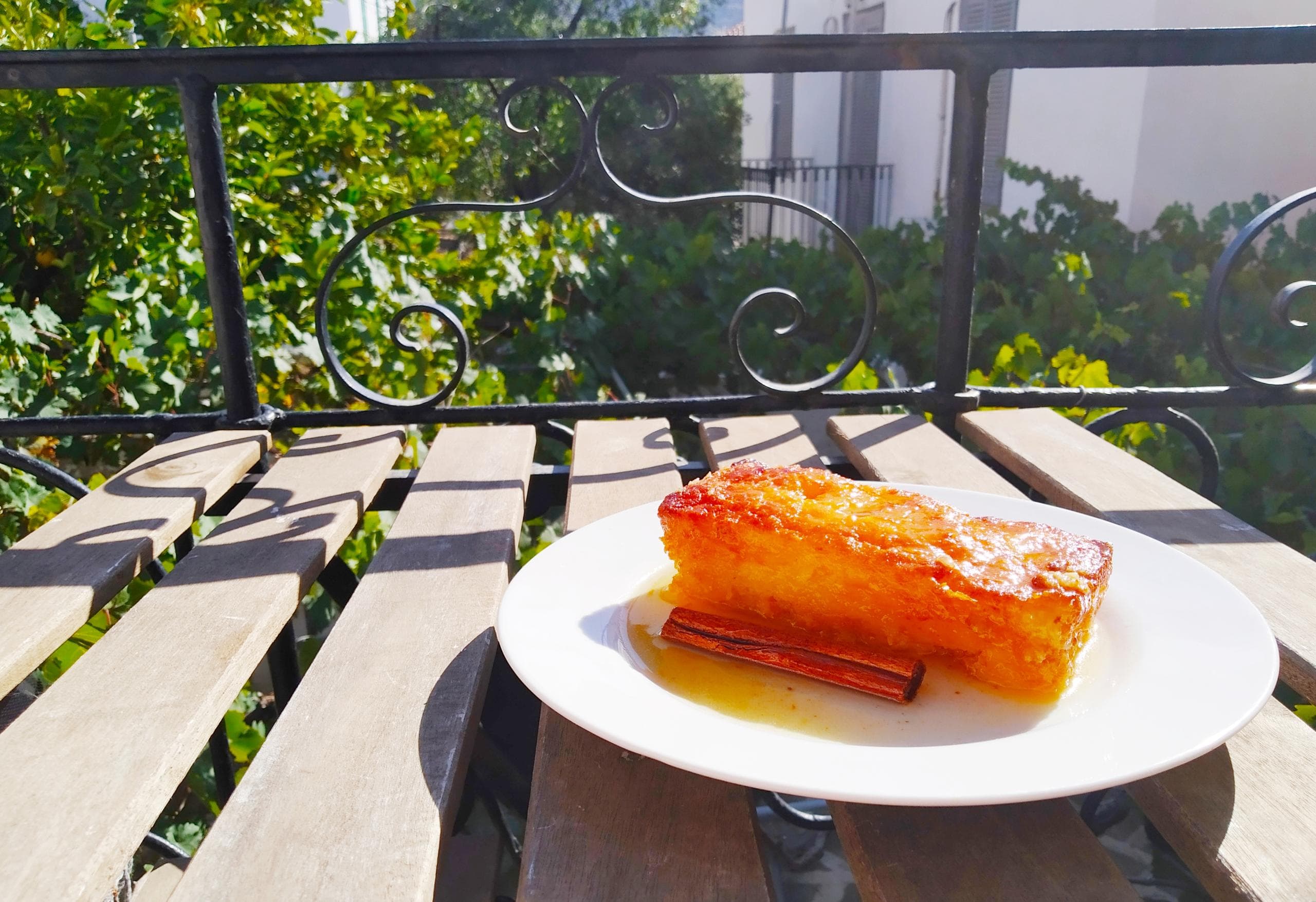 Sunlit plate of dessert on balcony table overlooking greenery