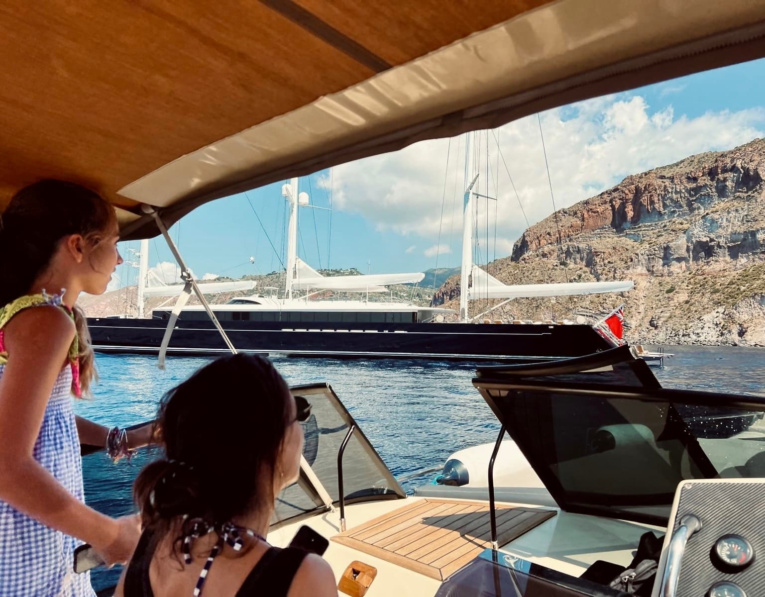 Passengers enjoying motorboat cruise past rocky coastal cliffs