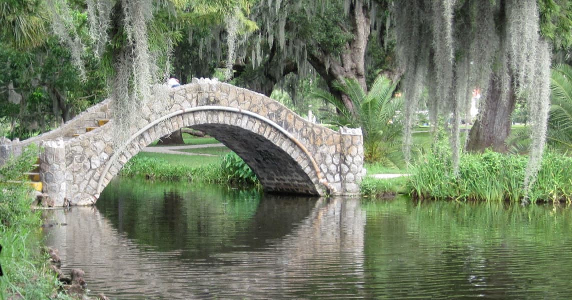 Stone arch bridge in City Park over reflective pond, scenic stroll