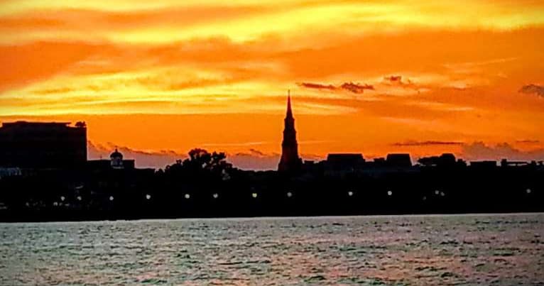 City skyline sunset over water with silhouetted steeple