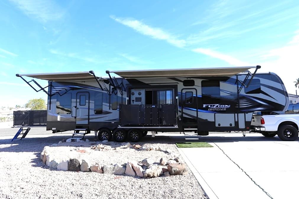 Fifth-wheel RV parked under blue sky at desert RV campsite
