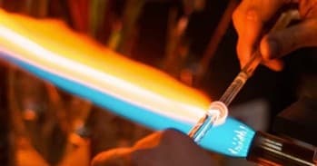 Glassblowing torch shaping molten glass in studio workshop