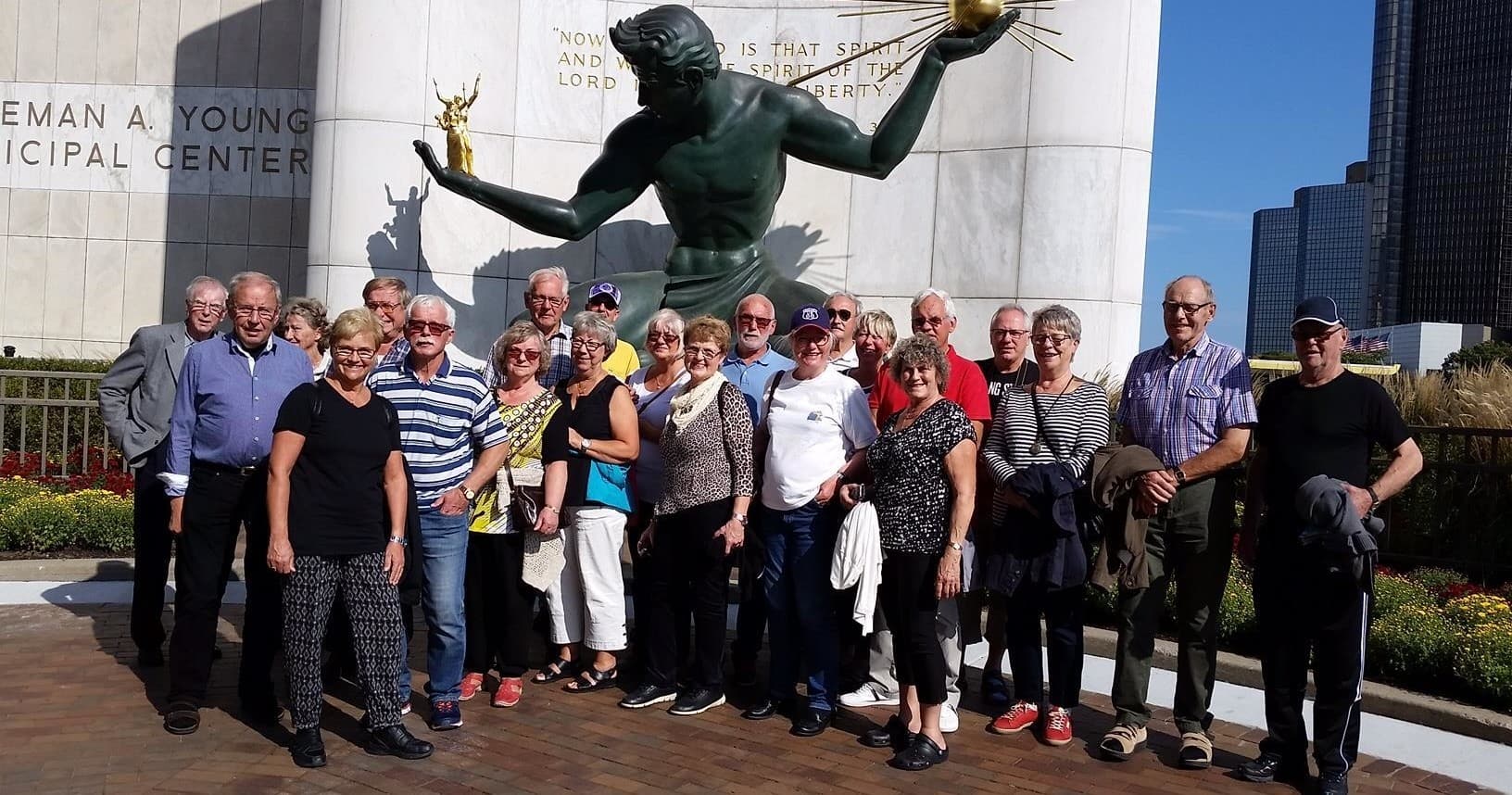 Tour group posing at Detroit's Spirit of Detroit statue outdoor city tour