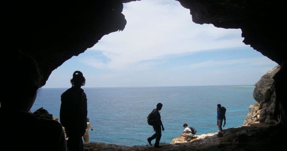 Coastal sea cave with silhouetted hikers viewing ocean horizon