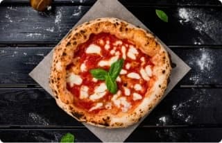 Neapolitan pizza served on rustic wood table with basil garnish
