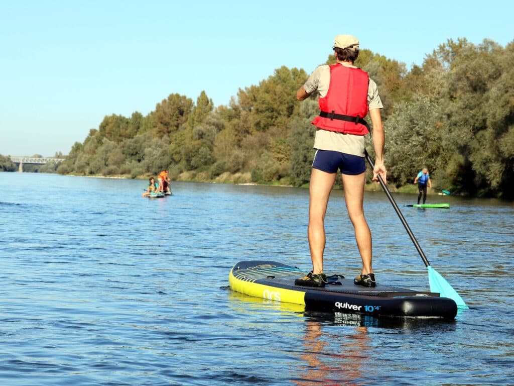 Stand-up paddleboarding on calm river with open water vista