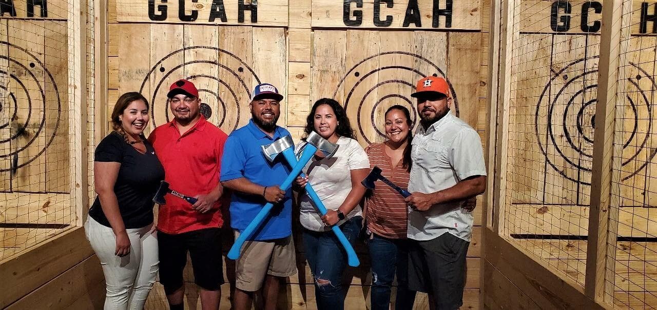 Group posing after indoor axe throwing at wooden target lanes